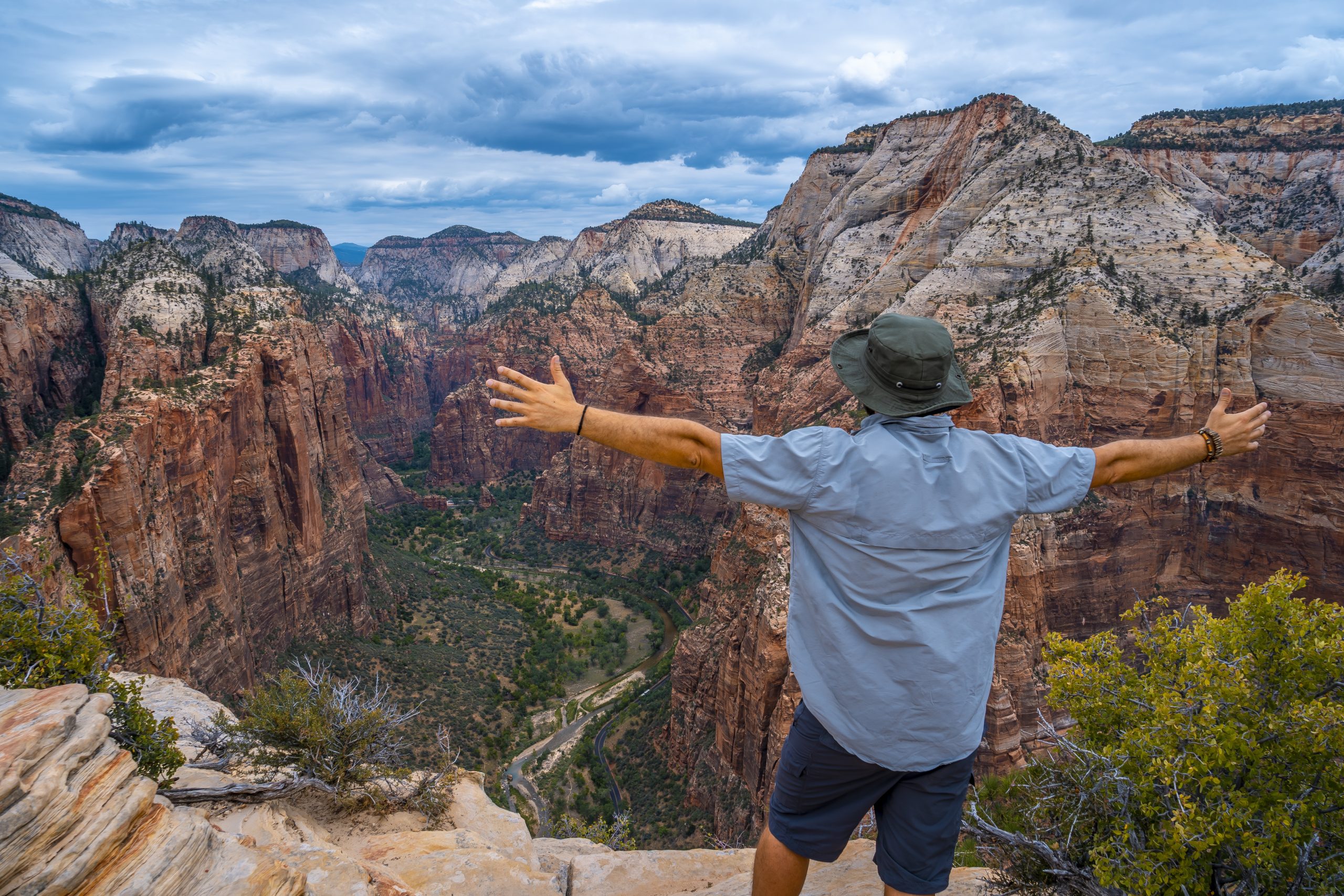 Male standing on top of the rock formations with stretched arms in Zion National Park, USA